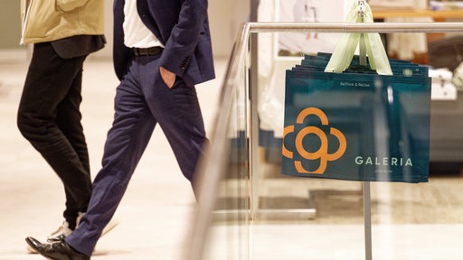 Taschen mit dem Firmen-Logo hängen in der neueröffneten Galeria-Filiale in Euskirchen für die Kunden bereit