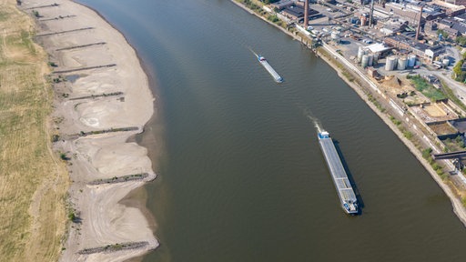 Am Rhein in Duisburg fahren Schiffe in der Fahrrinne, am Ufer sind breite Sandbänke sichtbar, die bei normalem Wasserstand unter Wasser sind. 
