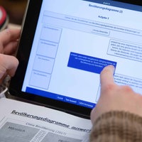 Eine Schülerin arbeitet an einem Tablet, daneben liegt ein Block und ein Stiftemäppchen 