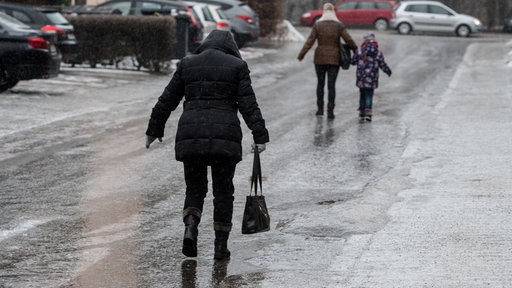 Passanten gehen vorsichtig auf einer vereisten Straße