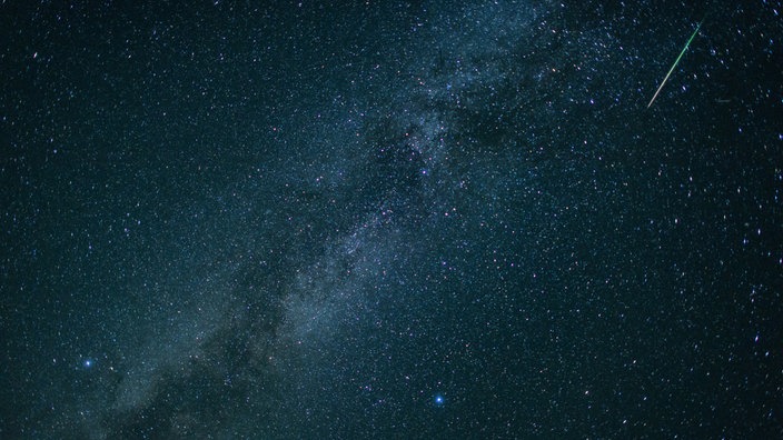 Eine Sternschnuppe leuchtet neben der Milchstraße am Himmel