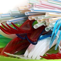 Plastikbesteck farbig und weiss mit Trinkhalmen auf einem Plastikteller