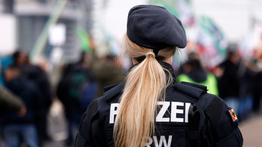 Eine Polizistin bei einer Demo von hinten.