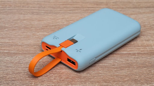 Eine hellblaue Powerbank mit orangefarbenem USB-Kabel