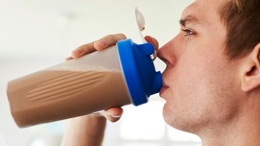 Ein junger Mann trinkt einen Proteinshake.