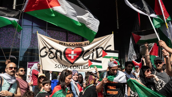 Protestanten halten ein Plakat mit der Aufschrift "Welcome To Genocide Song Contest"