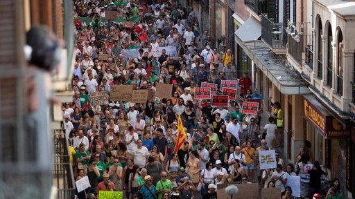 Zahlreiche Menschen ziehen durch die Straßen in Palma bei einer Demonstartion und halten Schilder hoch