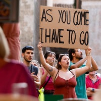 Eine Frau hält ein Schild mit der Aufschrift "As you come - I have to go" bei der Demo gegen Massentourismus hoch