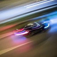 Ein schwarzes Auto rast über eine Straße.