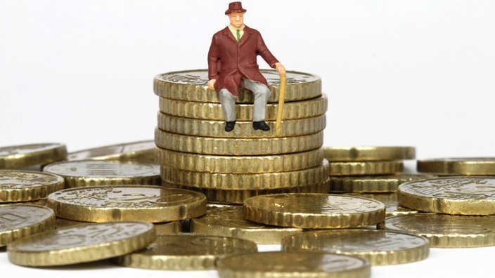 Eine kleine Modellfigur sitzt auf einem Münzstapel aus Euro-Cent-Münzen