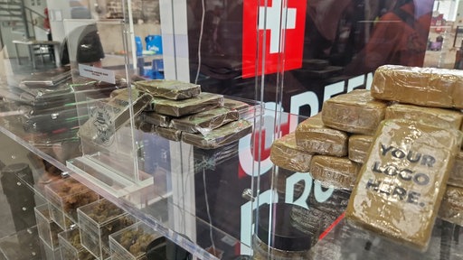 Braune Päckchen mit Cannabis liegen in einer Glasvitriene
