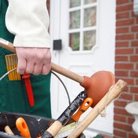 Ein Handwerker steht vor der Haustür mit Werkzeugeimer 