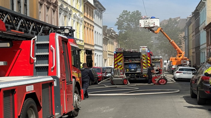Mehrere Feuerwehrfahrzeuge stehen mit ausgefahrenem Kran am Einsatzort.