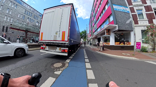 Bild aus der Perspektive eines Radfahrers der über eine Kreuzung fährt die voll mit Autos und Lkw ist.