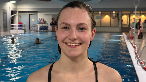 Ein Mädchen im Badeanzug steht in einer Schwimmhalle.
