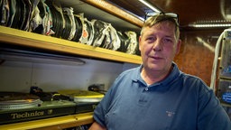 Peter Buchholz von der Raupenbahn steht vor den Schallplatten, die schon seit 100 Jahren für Musik auf dem Fahrgeschäft sorgen.