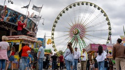 Fahrgeschäfte, Imbissbuden und Besucher vor dem Riesenrad der Rheinkirmes.