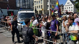 Polizist und Demonstranten mit Regenbogenfahnen stehen sich gegenüber