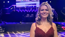 Gelsenkirchener Abiturientin Charlotte lächelnd auf ihrem Abiball in einem roten Kleid 