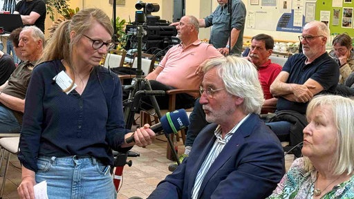 Die Moderatorin Rike Ullrich im Gespräch mit einem Mann aus dem Publikum