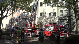 Ein Feuerwehrkran steht vor dem Mehrfamilienhaus mit der eingestürtzten Decke.