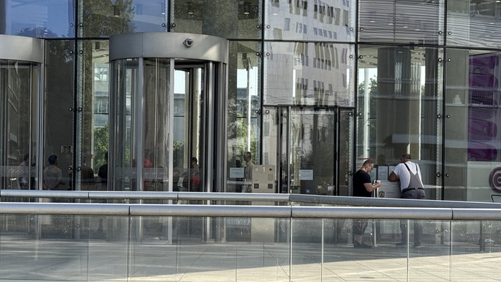 Zwei Handwerker stehen vor dem Eingang des Evonik-Towers. 