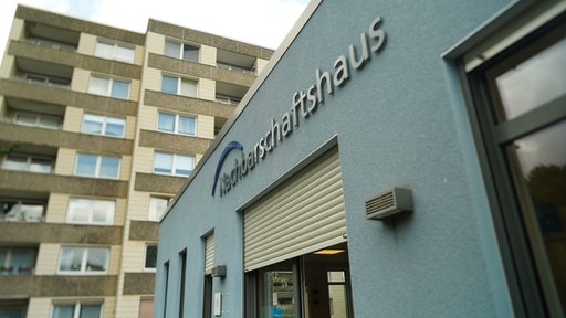 Das Nachbarschaftshaus steht auf einer blauen Hausfassade. 
