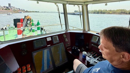 Schiffsführer Andé Bruins schaut am Ruder des WSA-Arbeitsbootes "Emmerich" auf den Rhein