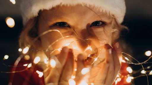 Ein Mädchen hält eine Lichterkette in der Hand