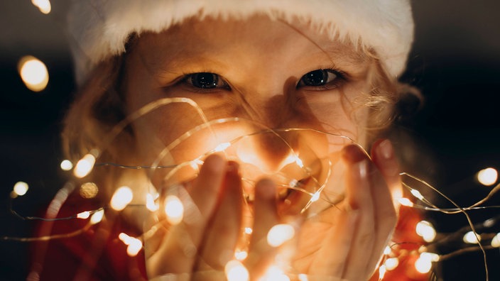 Ein Mädchen hält eine Lichterkette in der Hand