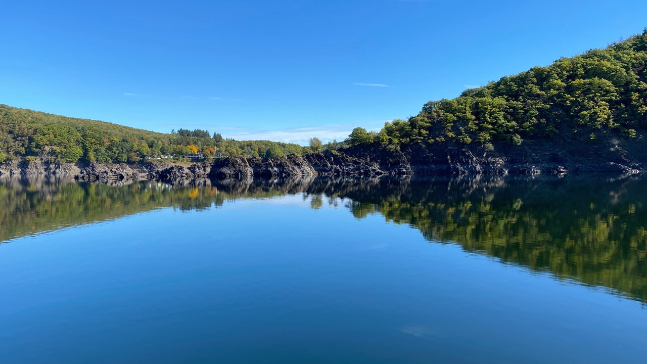Rursee in der Eifel mit blauem Himmel und Wald