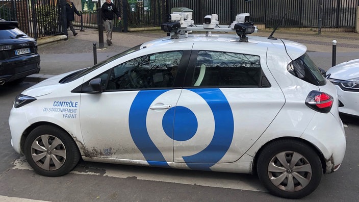 Ein kleines, weißes Auto mit Kameras auf dem Dach