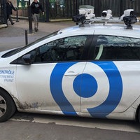 Ein kleines, weißes Auto mit Kameras auf dem Dach