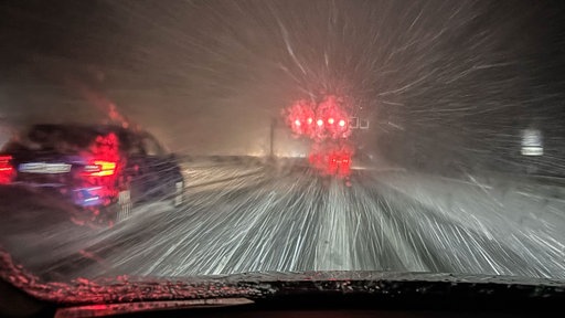 Ein Auto fährt im Schneetreiben über die Autobahn 