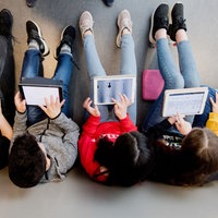 Schüler sitzen auf dem Boden mit ihren IPads und lernen