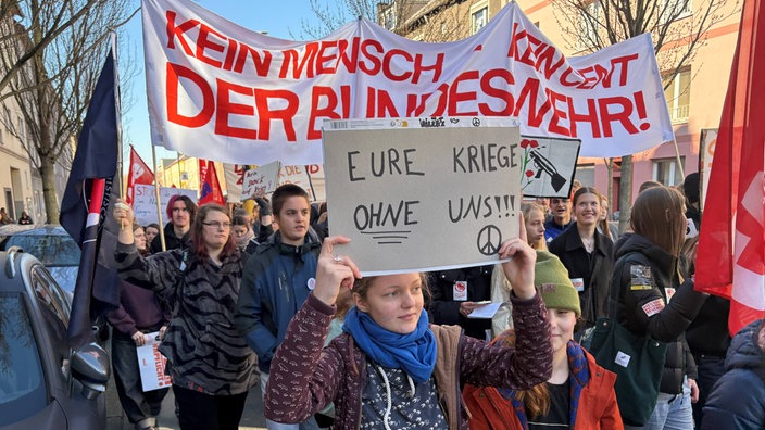 Bei einer Demo hält ein Mädchen ein Schild mit der Aufschrift "Eure Kriege ohne uns"