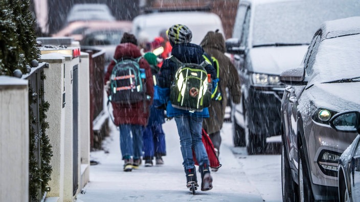 Grundschüler laufen über schneebedeckte Gehwege