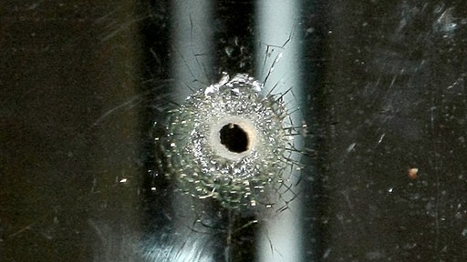 Symbolbild eines Schusslochs in einem Fenster