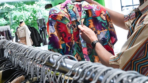 Mitarbeiter sortiert in einem Modeladen Secondhand-Kleidung