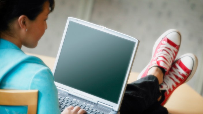 Eine junge Frau hat einen Laptop auf ihrem Schoß