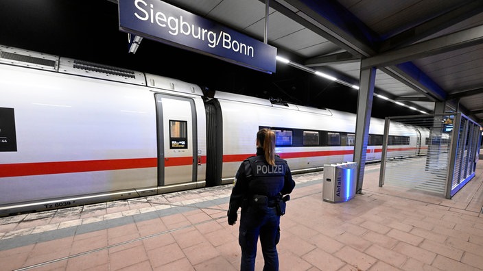 Polizistin steht am Siegburger Bahnhof vor dem ICE, in dem sich der Vorfall ereignet hat