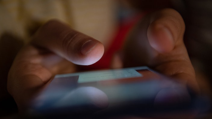Ein Smartphone wird gehalten. 