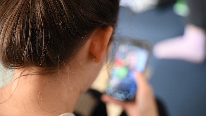 Eine junge Frau schaut auf ihr Smartphone