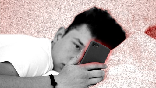Ein Jugendlicher schaut im Bett auf sein Smartphone