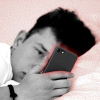 Ein Jugendlicher schaut im Bett auf sein Smartphone