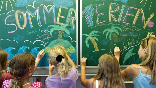 Schülerinnen gestalten eine Schultafel zum Ferienbeginn