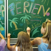 Schülerinnen gestalten eine Schultafel zum Ferienbeginn