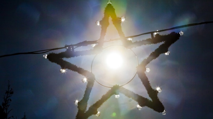 Die Sonne scheint vom blauen Himmel durch einen Weihnachtsstern
