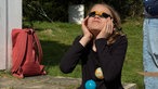 Die neunjährige Clara beobachtet die Sonnenfinsternis von der Sternwarte Essen aus mit einer speziellen Sonnenfinsternis-Brille.