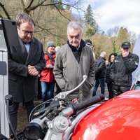 Innenminister Herbert Reul und NRW-Verkehrsminister Oliver Krischer schauen sich ein ausgestelltes Unfallmotorrads an.